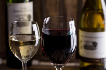 木の背景で赤ワインと白ワインのボトルとワイングラスがオシャレにおいてあるワインバー