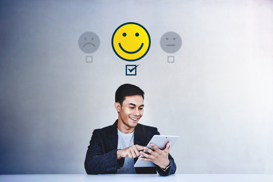 Customer Experience Concept. Young Businessman Giving his Positive Review in Satisfaction Online Survey. Happy Client Submit a Smiling Face for Excellent Services via Tablet