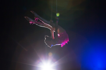 Circus artist acrobat performance. The girl performs acrobatic elements in the air. Circus gymnast on the stage