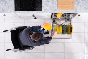 Handicapped Man Arranging Plates In Dishwasher