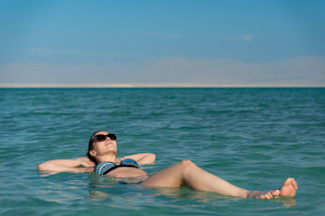 young woman floating on the water surface of the dead sea