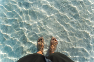 man's foot in warm clear water in the Dead sea