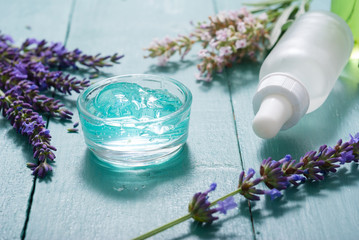 cream, shampoo, perfume product samples with lavender on old blue wood table background