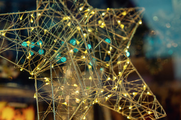 Holidays concept. Evening golden star lights outdoors glowing. New Year celebration. Decorated and illuminated Christmas street at night. Abstract blurred background. Toned image. Selective focus.