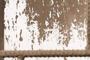 Old painted window behind iron bar close up. Grunge background in brown color