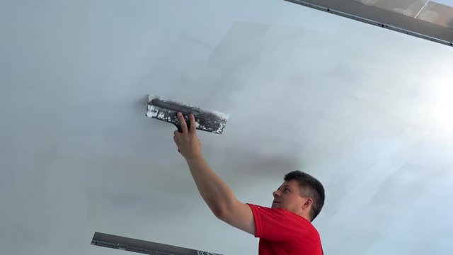 Plasterer apply plaster with trowel on ceiling
