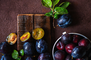 Fresh plums in drops with leaves. Fruits. On a dark wooden background. Top view. Free space for your text. Toned image. Selective focus.