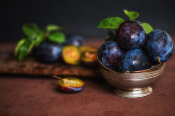 Bowl with ripe juicy plums on table. Fresh organic plums. Summer harvest. Autumn harvest. Beautiful still life. Toned image. Selective focus.