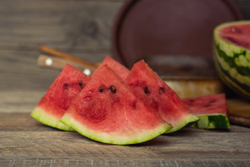 Bright juicy watermelon on a rustic vintage background. Half refreshing berries top view and soft focus. Healthy diet and vegetarian meals in the summer. Toned vintage image.