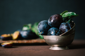 Organic fresh plums in silver vintage bowl on brown surface background. Healthy lifestyle summer...