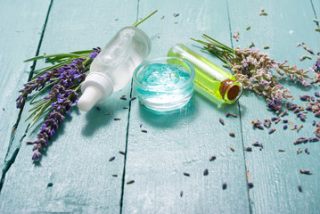 cream, shampoo, perfume product samples with lavender on old blue wood table background