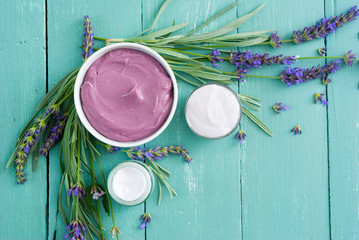 cosmetic creams and lavender flowers on blue wooden table