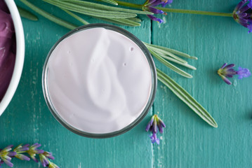 cosmetic creams and lavender flowers on blue wooden table