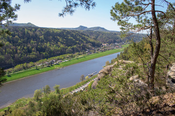 Fototapeta na wymiar Saxon Switzerland - Germany main attraction. View from Bastei in view of a German town, sandy cliffs and the river Elbe on a sunny spring day