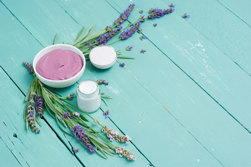 cosmetic creams and lavender flowers on blue wooden table