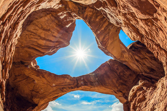 Amazing rock formations at Arches National Park in southern Utah. View from below of Double Arch looking back up at the sun.