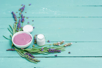 cosmetic creams and lavender flowers on blue wooden table