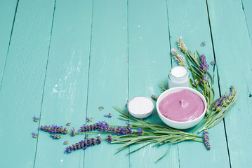cosmetic creams and lavender flowers on blue wooden table