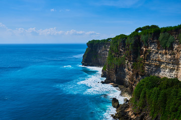 Fototapeta na wymiar Azure beach with rocky mountains and clear water with huge waves of Indian ocean at sunny day. View of Uluwatu cliff and blue sea in Bali, Indonesia. Beautiful world, travel, holiday.