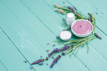 cosmetic creams and lavender flowers on blue wooden table
