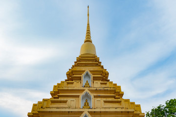 A golden triangle pagoda with buddha statutes and blue sky on background in Songkhla City Thailand.