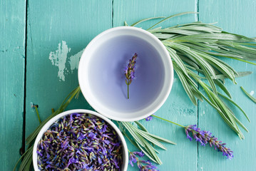 cup of lavender tea with a pile of fresh flowers, syrup, sugar candy on blue wood table background