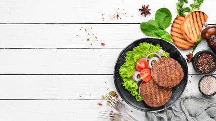 fried cutlet for burger with vegetables. In a black plate on a wooden background Top view. Free...