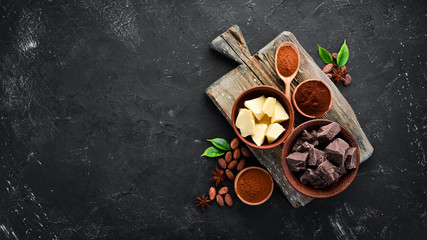 Cocoa beans, chocolate, cocoa butter and cocoa powder on a black background. Top view. Free copy...