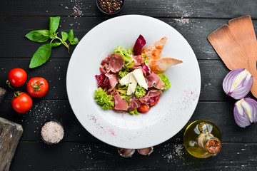 Vegetable salad with brie cheese and prosciutto. In the plate. Top view. Free space for your text. Rustic style.
