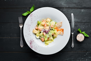 Vegetable Caesar salad with salmon. In the plate. Top view. Free space for your text. Rustic style.