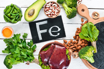 Food containing natural iron. Fe: Liver, avocado, broccoli, spinach, parsley, beans, nuts, on a...