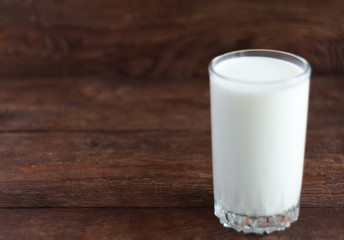 a glass of cow's milk on a wooden background