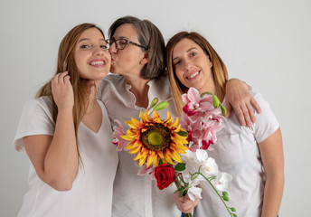 mother and two twin sisters enjoy in very funny attitude with a big sunflower in their hands