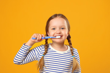 Little child girl in striped pajamas brushing her teeth with a toothbrush. The concept of daily...