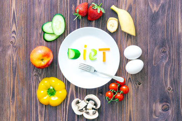 white plate and fork, vegetables, strawberries, two eggs, mushrooms, Apple on wooden background. The inscription vegetables 