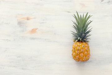 Ripe pineapple over white wooden background. Beach and tropical theme. Top view