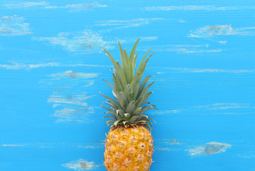 Ripe pineapple over blue wooden background. Beach and tropical theme. Top view