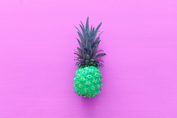 abstract photo of green pineapple over pink wooden background. Beach and tropical theme. Top view
