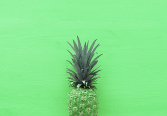 abstract photo of pineapple over green wooden background. Beach and tropical theme. Top view