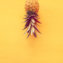 Ripe pineapple over yellow wooden background. Beach and tropical theme. Top view