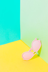 Fashionable art set with pink sunglasses in bright colors on bold background in the corner. Strong shadows.