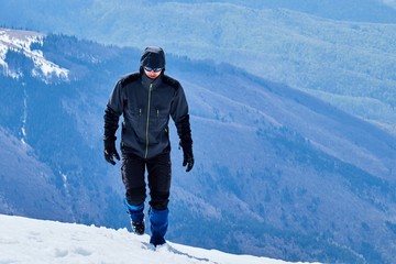 Fototapeta na wymiar tourist mountaineer climbs over the snowy mountains to the summit