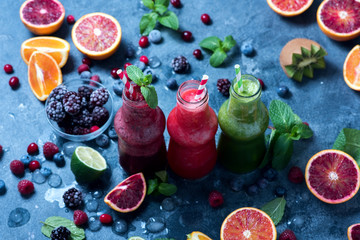 Colorful smoothies in bottles with berries and citrus fruits, healthy vitamin drink