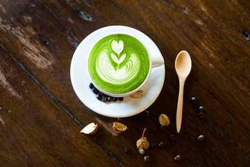 matcha latte art with coffee bean and wood spoon on wood table