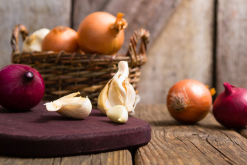 Fototapeta na wymiar onions and garlics on cutting board, weathered wooden background