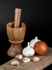 Wooden mortar (pounder), pestle, onion, garlic and other vegetables isolated on black