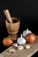 Wooden mortar (pounder), pestle, onion, garlic and other vegetables isolated on black