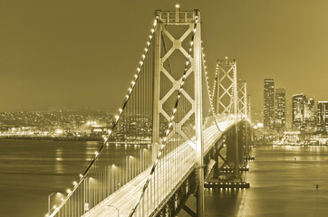 View of Bay Bridge across San Francisco Bay with lots of cars passing through in San Francisco at night.