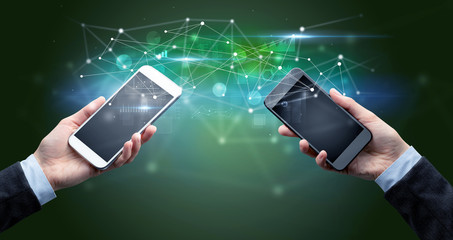 Close up of two hands holding smartphones and sharing business data