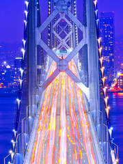 Obrazy na Szkle  Widok Bay Bridge przez zatokę San Francisco z dużą ilością samochodów przejeżdżających w San Francisco w nocy.
